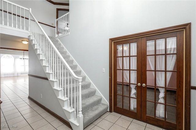 staircase featuring tile patterned floors, a notable chandelier, and french doors