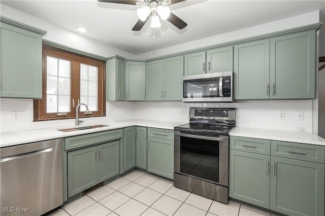 kitchen with decorative backsplash, appliances with stainless steel finishes, ceiling fan, sink, and green cabinetry