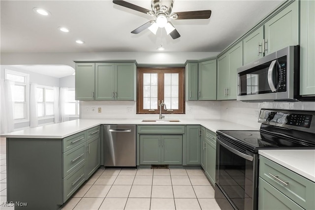 kitchen featuring sink, stainless steel appliances, kitchen peninsula, light tile patterned floors, and green cabinetry