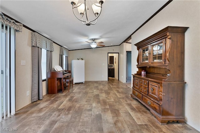 interior space with crown molding, wood-type flooring, and ceiling fan with notable chandelier