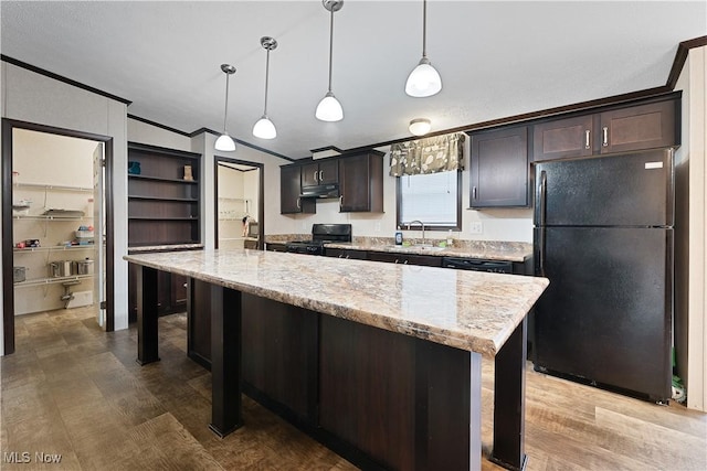 kitchen with dark brown cabinets, crown molding, black appliances, hanging light fixtures, and an island with sink