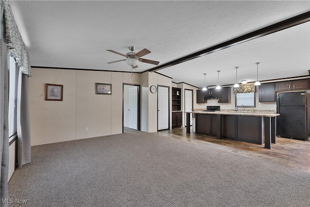 unfurnished living room with dark colored carpet, sink, ceiling fan, a textured ceiling, and beam ceiling