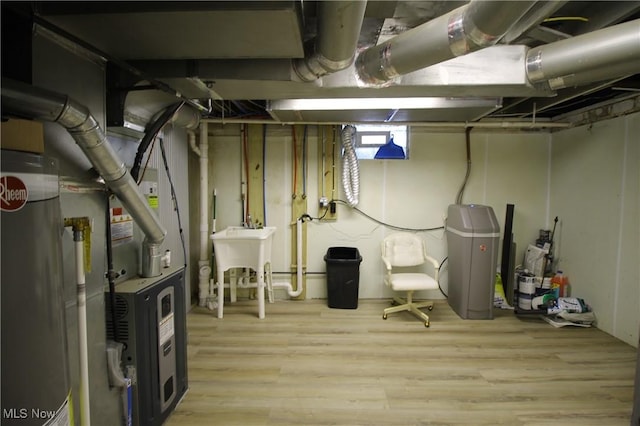 basement with hardwood / wood-style floors, gas water heater, and sink