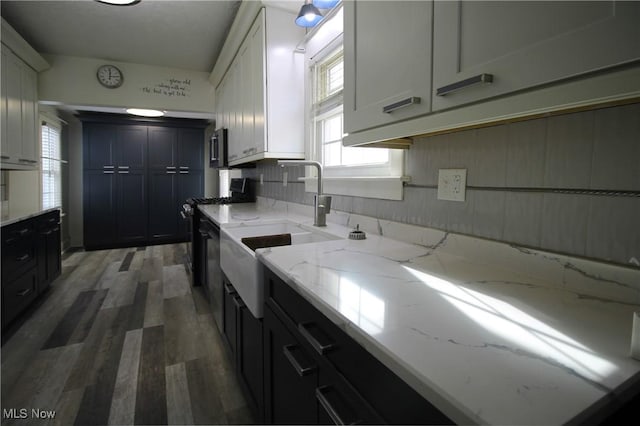 kitchen featuring light stone countertops, sink, black gas range, dark hardwood / wood-style floors, and white cabinetry