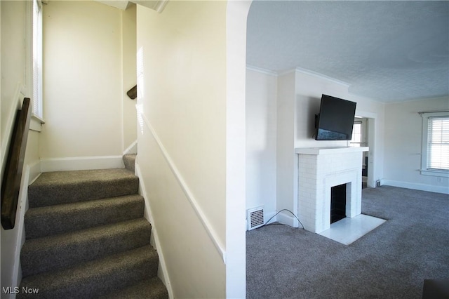 staircase featuring carpet flooring, a brick fireplace, and crown molding