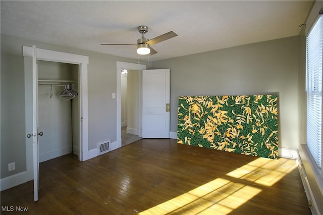 unfurnished bedroom with multiple windows, ceiling fan, a closet, and dark hardwood / wood-style floors