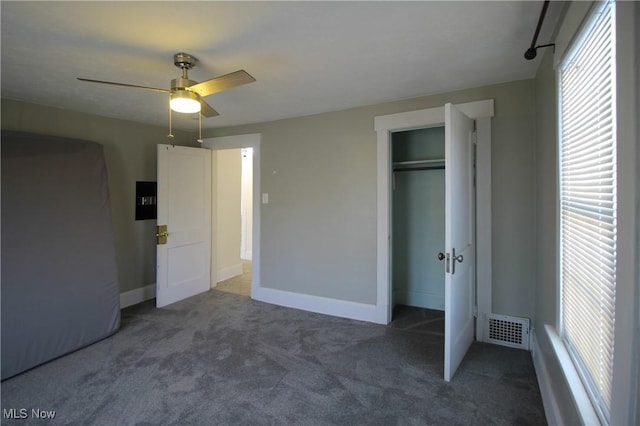 unfurnished bedroom featuring dark colored carpet, a closet, and ceiling fan