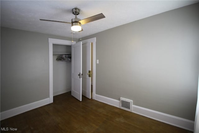 unfurnished bedroom with dark hardwood / wood-style flooring, a closet, and ceiling fan