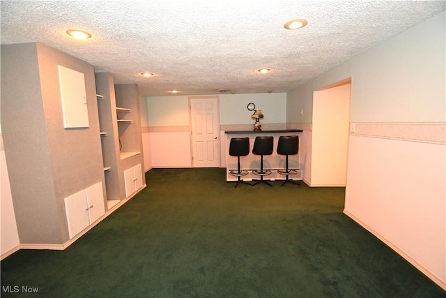 basement featuring dark carpet and a textured ceiling