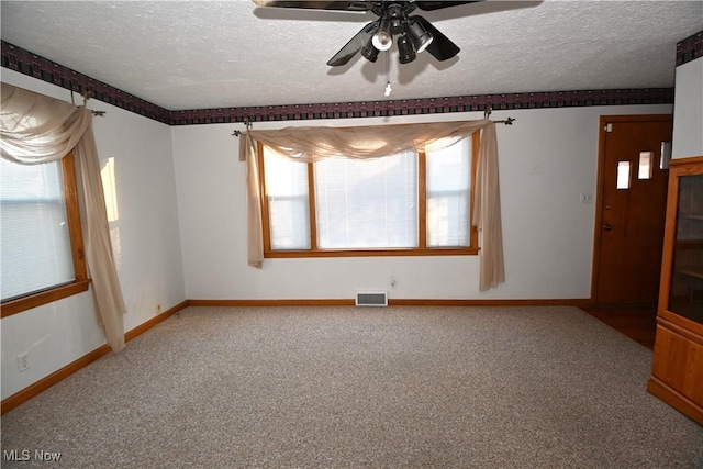 carpeted spare room with a textured ceiling, ceiling fan, and a healthy amount of sunlight