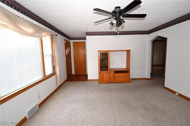 carpeted spare room featuring ceiling fan and a textured ceiling