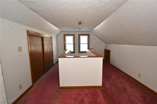 interior space with dark carpet, a textured ceiling, and vaulted ceiling