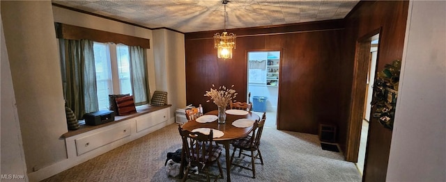 carpeted dining space with ornamental molding and a notable chandelier