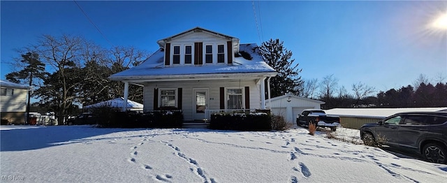 bungalow-style house with covered porch, a garage, and an outbuilding