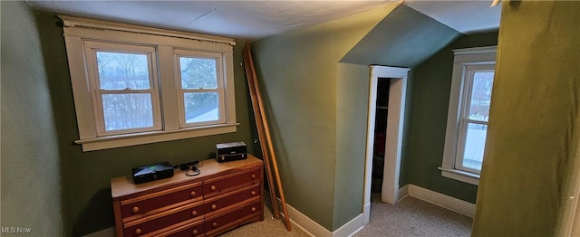 interior space with light colored carpet, a healthy amount of sunlight, and lofted ceiling