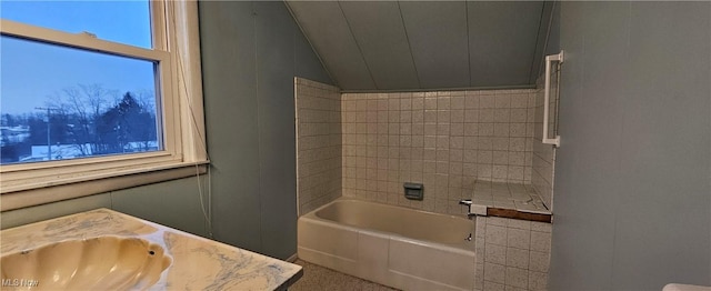 bathroom featuring a washtub, lofted ceiling, and vanity