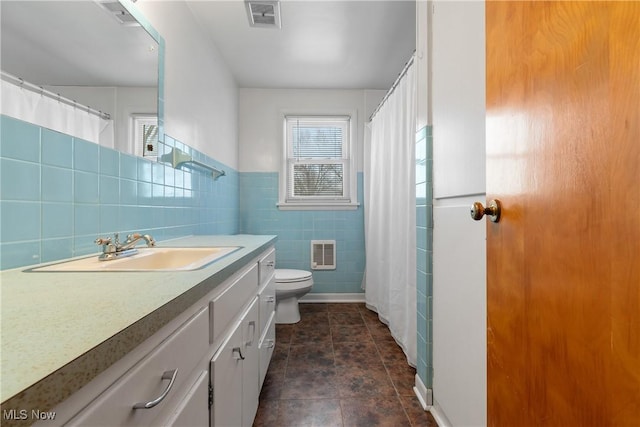 bathroom featuring vanity, toilet, and tile walls