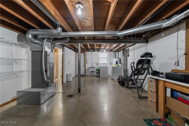 basement featuring electric water heater, sink, and washing machine and clothes dryer