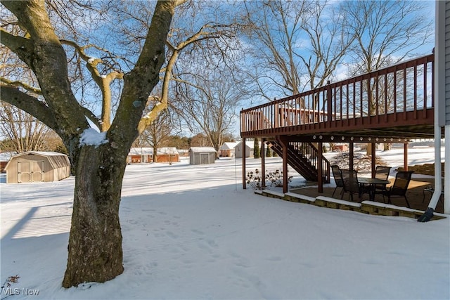 yard layered in snow with a shed and a deck