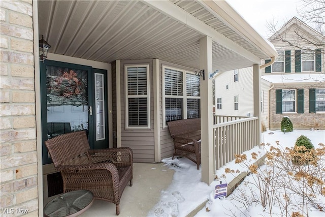 snow covered property entrance featuring a porch