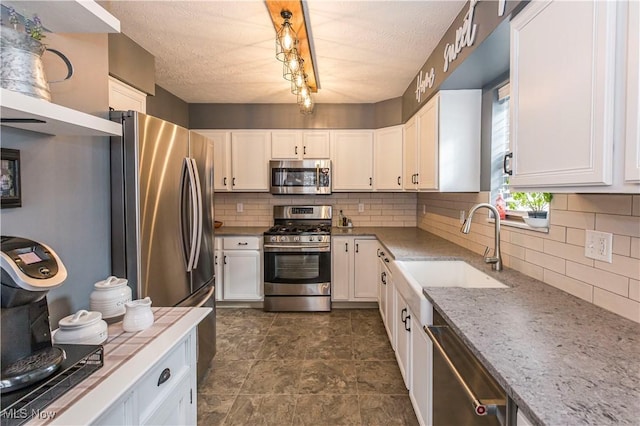 kitchen with stainless steel appliances, white cabinetry, tasteful backsplash, and sink