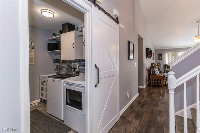 laundry area with cabinets, a textured ceiling, dark wood-type flooring, washer and dryer, and a barn door