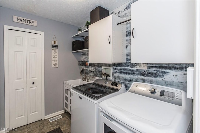 laundry area with cabinets, a textured ceiling, separate washer and dryer, and sink