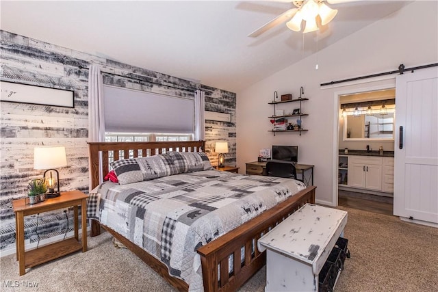 carpeted bedroom featuring ceiling fan, a barn door, lofted ceiling, and ensuite bathroom