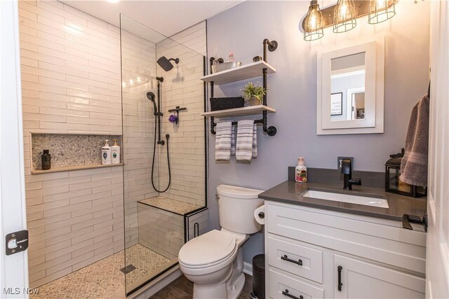 bathroom with a tile shower, vanity, and toilet