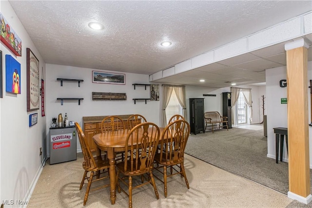 carpeted dining room with a textured ceiling