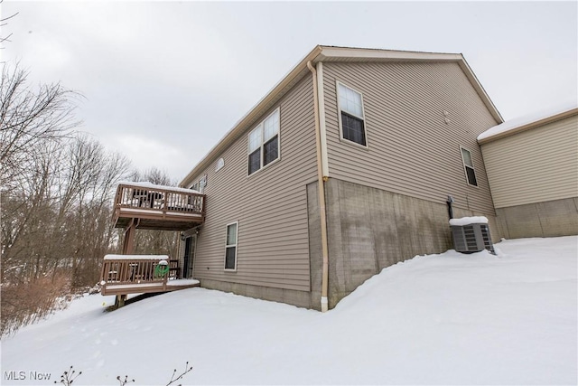 view of snow covered exterior with central AC unit and a deck