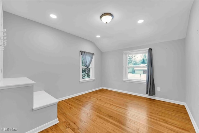 unfurnished room with hardwood / wood-style flooring and lofted ceiling