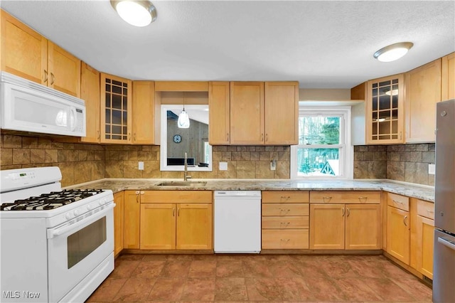 kitchen featuring light brown cabinets, white appliances, sink, hanging light fixtures, and light stone countertops