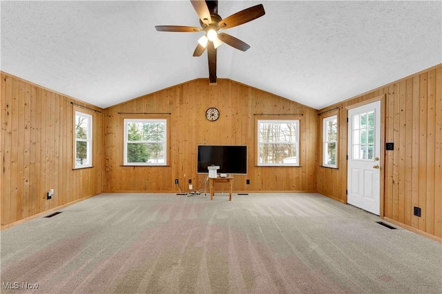 unfurnished living room featuring a textured ceiling, light colored carpet, vaulted ceiling, and ceiling fan