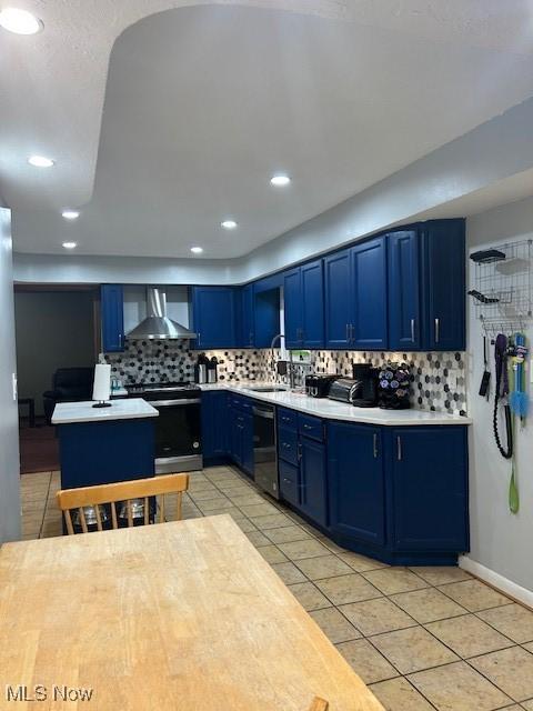 kitchen with light tile patterned floors, wall chimney exhaust hood, stainless steel range with electric stovetop, and blue cabinets