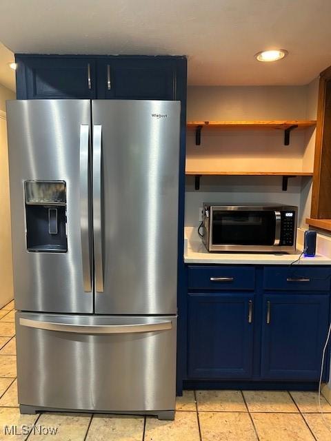 kitchen featuring light tile patterned floors, stainless steel appliances, and blue cabinets