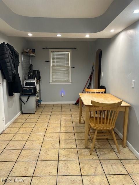 tiled dining space with a raised ceiling