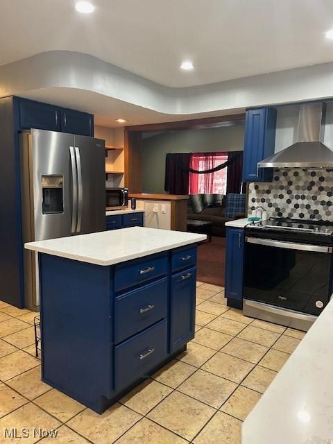 kitchen with wall chimney exhaust hood, a kitchen island, blue cabinets, and stainless steel appliances