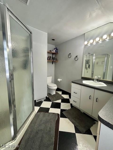 bathroom with vanity, toilet, and a shower with shower door