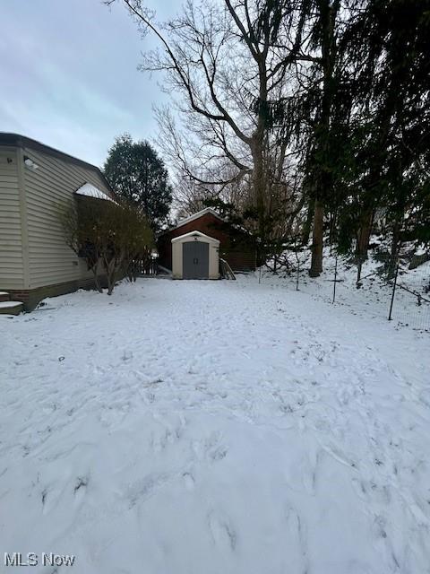 snowy yard featuring a storage unit