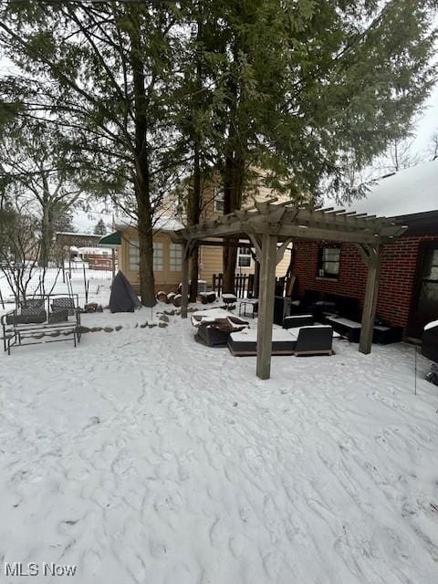 snowy yard with a deck and a pergola