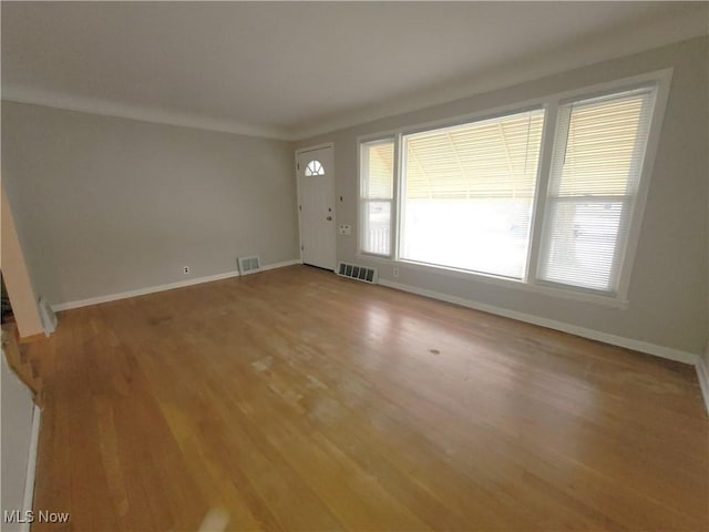 unfurnished living room featuring crown molding and wood-type flooring