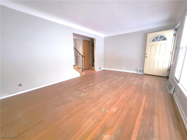 unfurnished living room with wood-type flooring and a wall mounted air conditioner