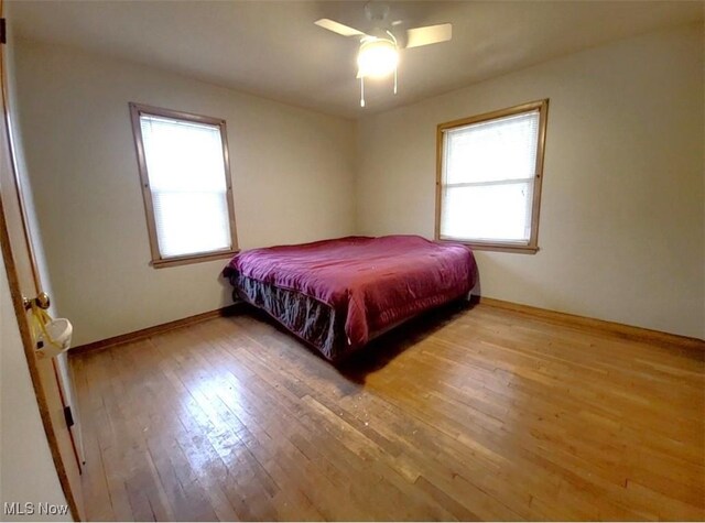 bedroom with multiple windows, ceiling fan, and hardwood / wood-style floors