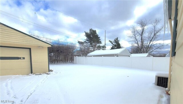 snowy yard featuring central AC and an outbuilding