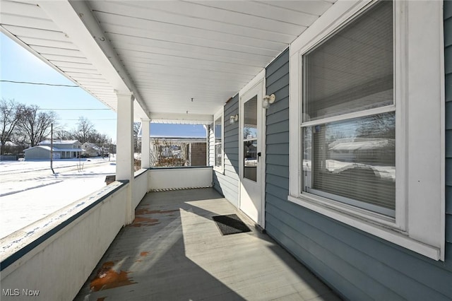 snow covered back of property featuring a porch