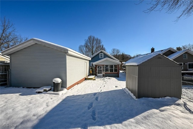 snowy yard featuring a storage unit and a sunroom