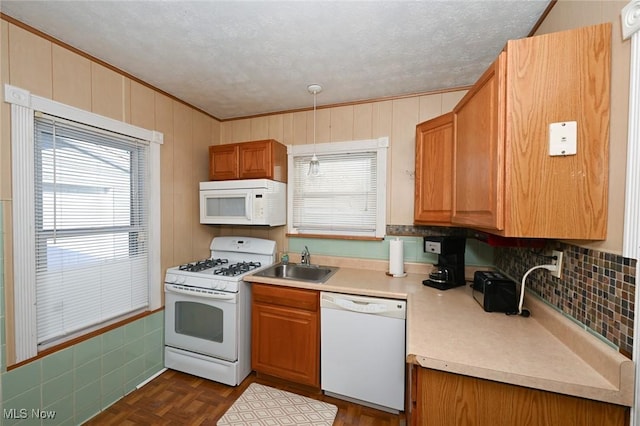 kitchen featuring plenty of natural light, dark parquet flooring, sink, and white appliances