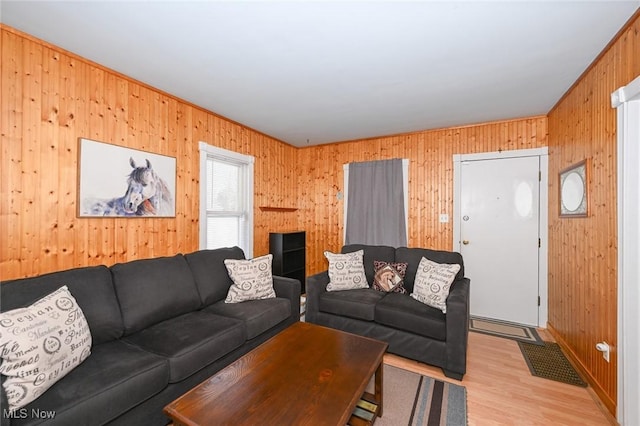 living room with light hardwood / wood-style floors and wooden walls