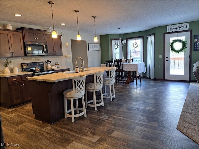 kitchen with pendant lighting, a center island with sink, sink, range with electric cooktop, and a textured ceiling